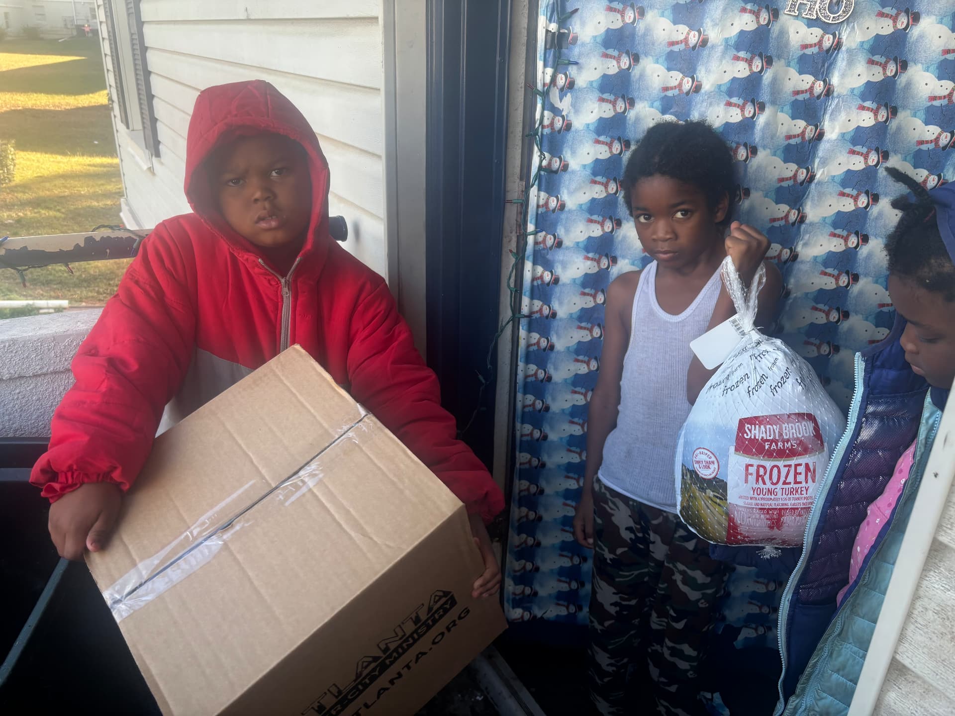 Kids waiting on the porch with their Thanksgiving box and turkey
