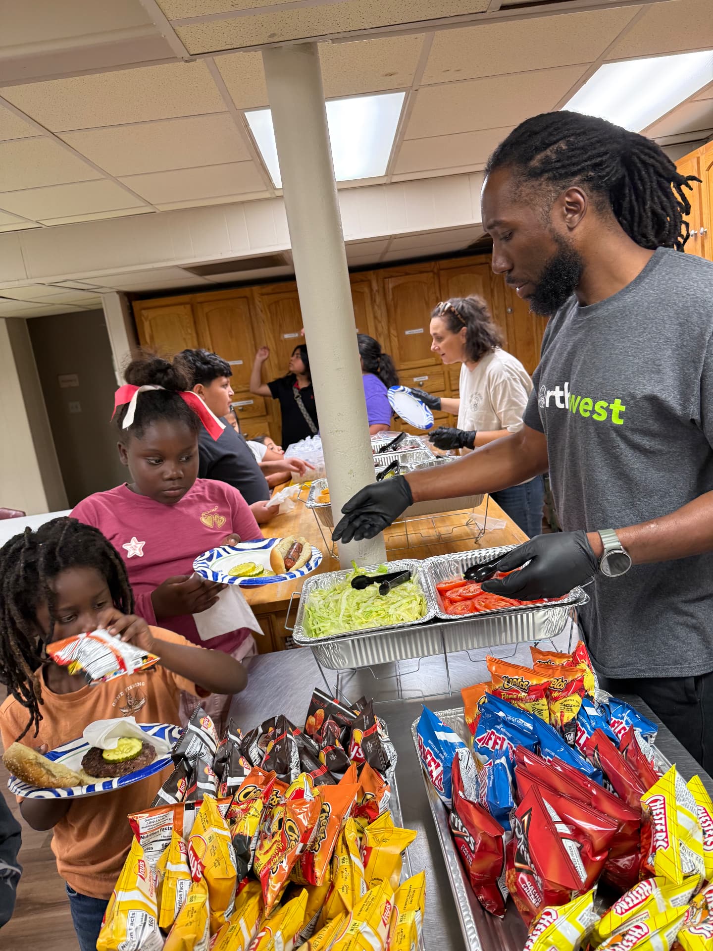 Partner volunteer serving dinner to kids at the AIM Family Center