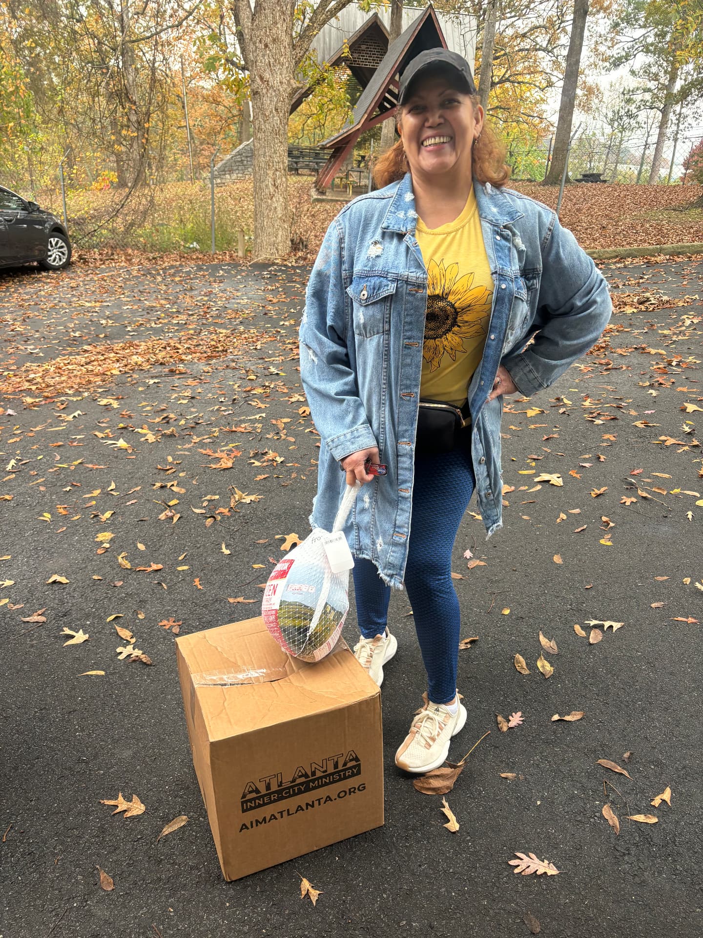 A volunteer with an AIM Thanksgiving In A Box and a frozen turkey