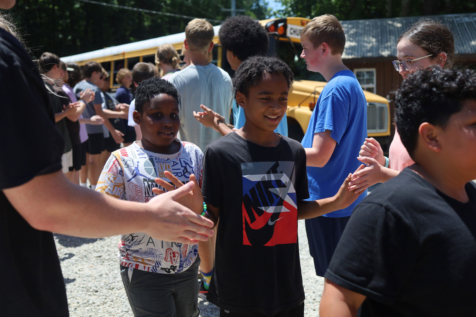 AIM volunteers greeting kids with high fives as they arrive off the bus