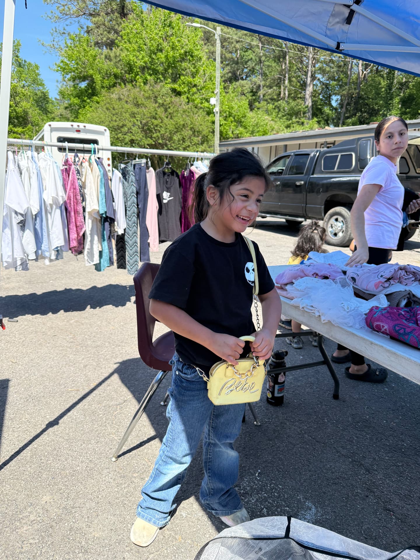 A young girl smiling at an AIM mobile distribution clothing table
