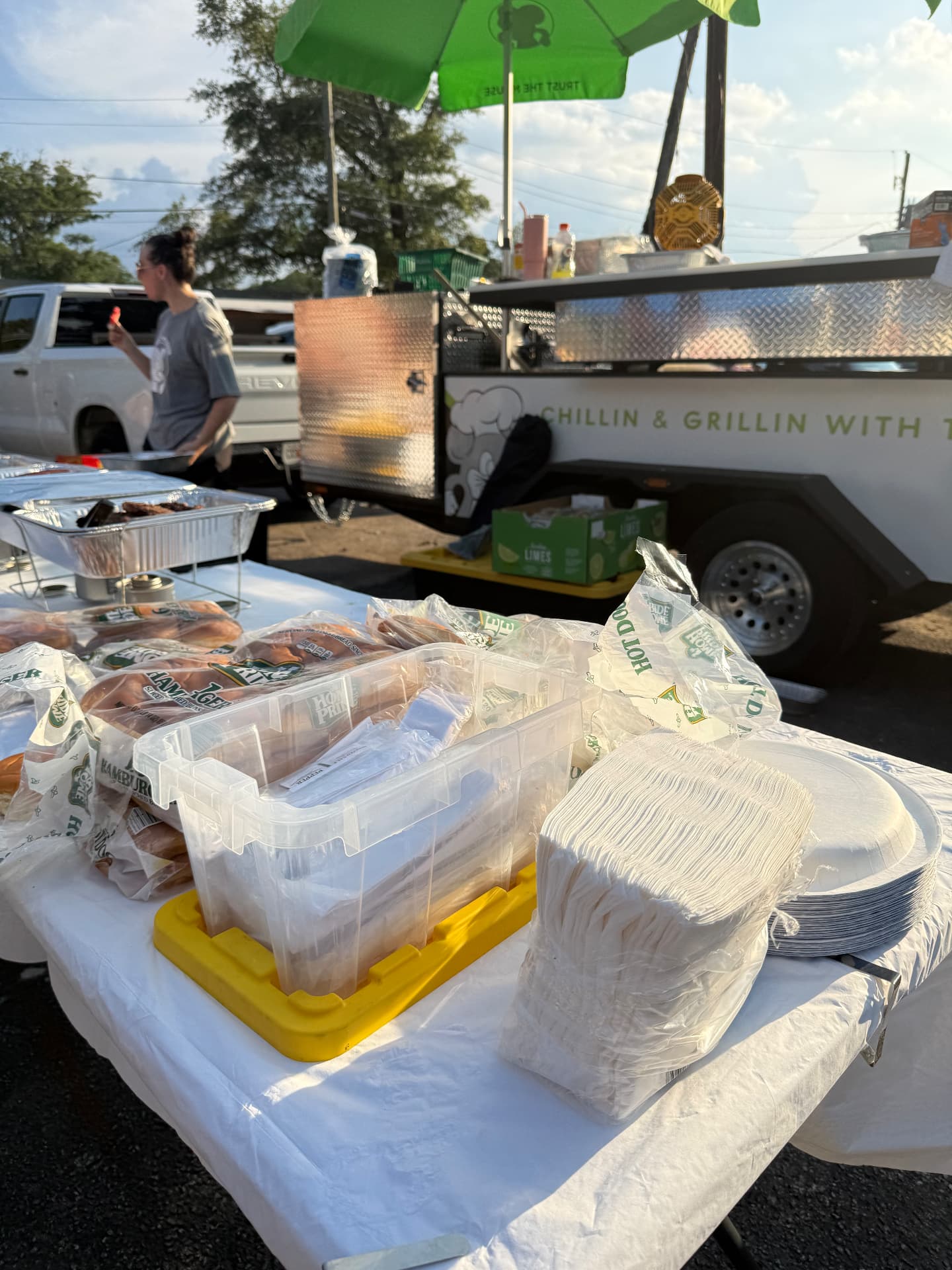 Table set with buns, plates, and napkins for a partner cookout